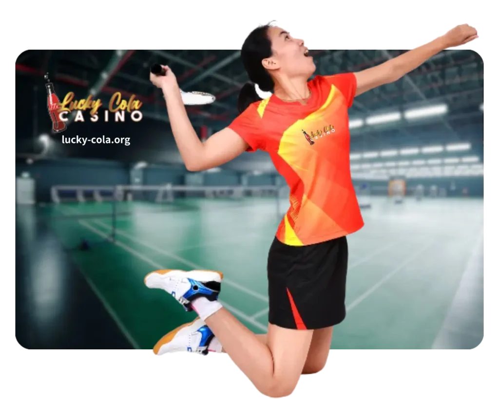 A female badminton player in a red sports outfit preparing to hit a shuttlecock with a racket on an indoor court.